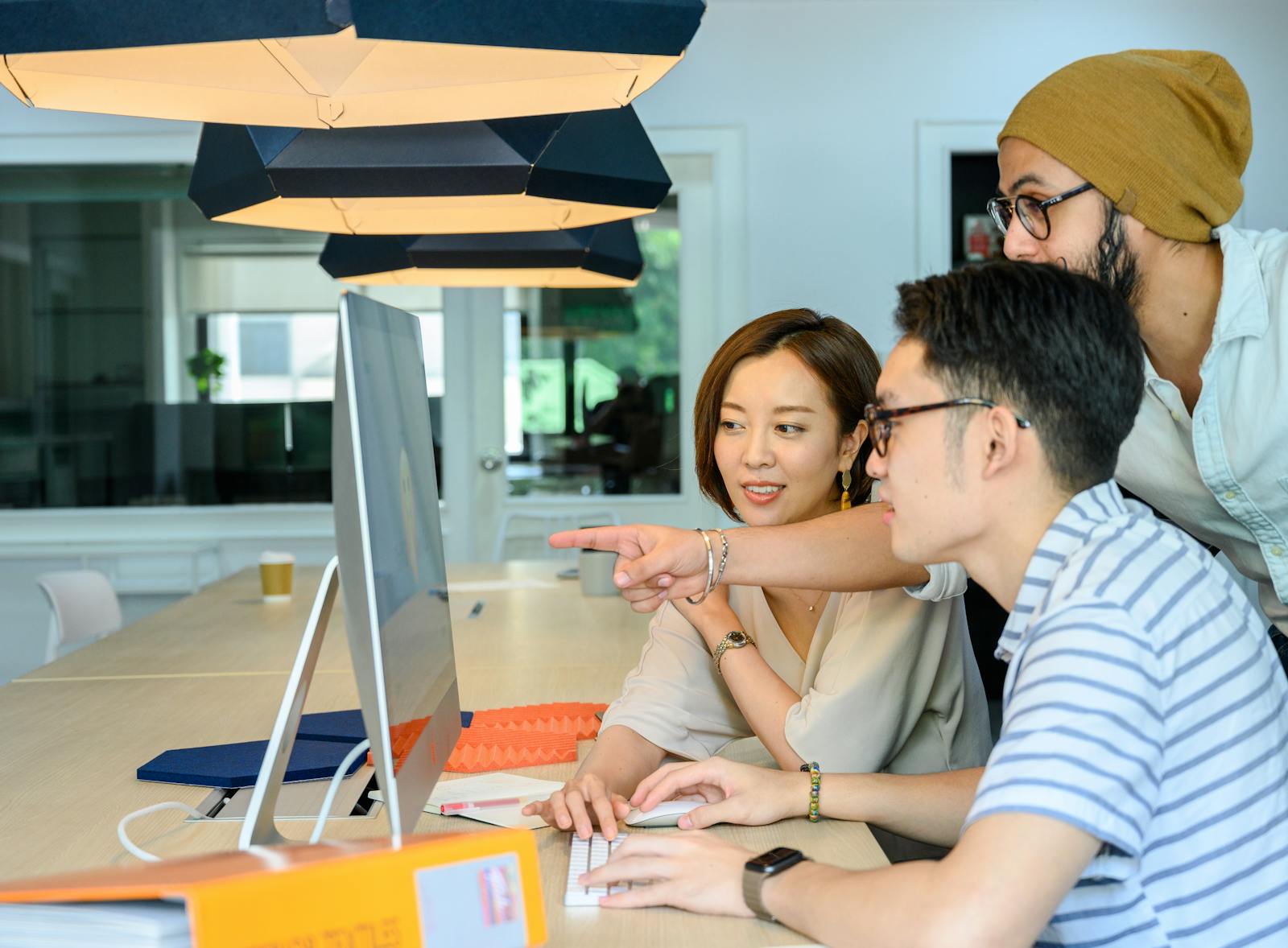 Three analysts collaborating around a computer monitor, walking through findings