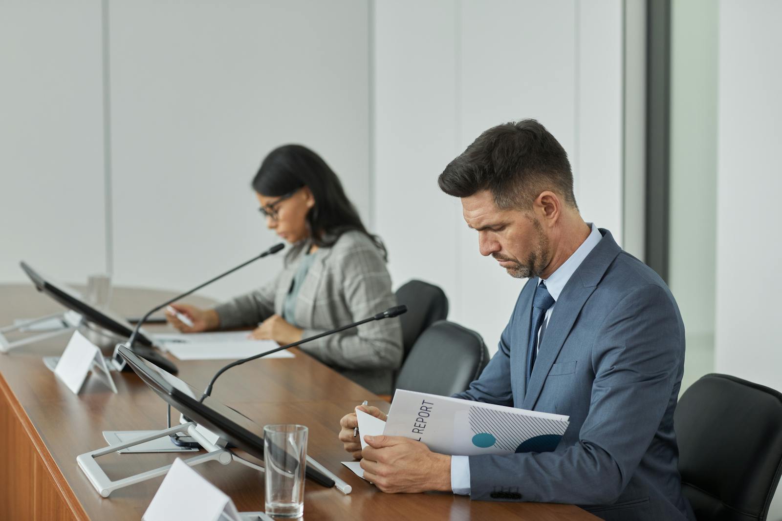 Professionals reviewing a policy report at a microphone-equipped conference table